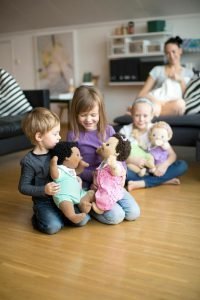 Varios niños aprendiendo a jugar con muñecas