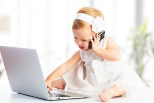 Niña pequeña usando un ordenador y un teléfono móvil