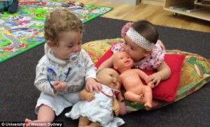 Foto de dos bebés aprendiendo a jugar con muñecas